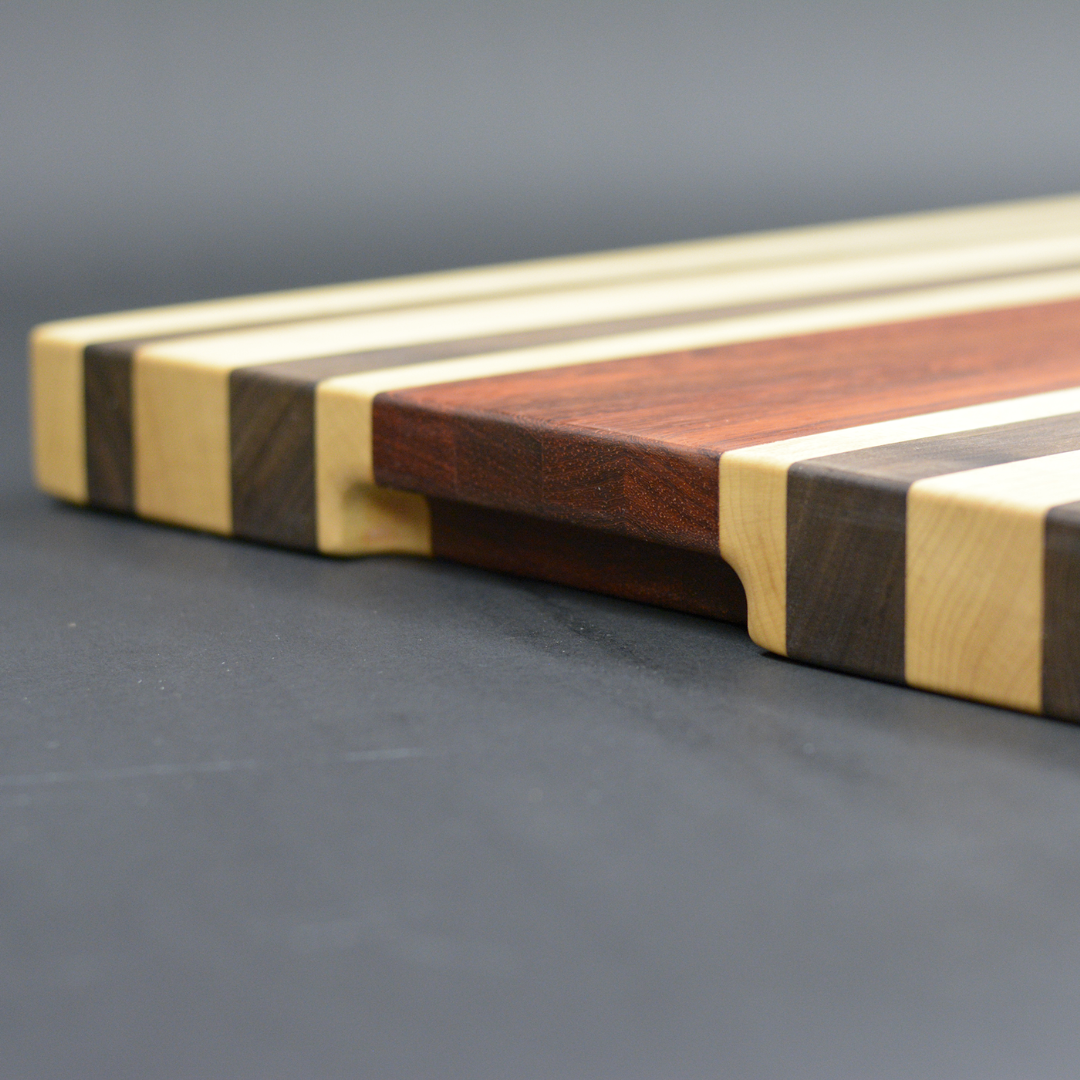 Handmade edge store grain cutting board made of walnut,cherry,and maple with built in handles and feet